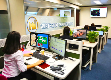 Ein mittleres Büro mit Menschen, Schreibtischen, Computern und lustigen Bildschirmhintergründen